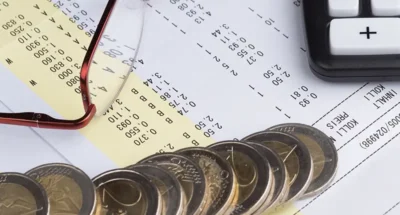 Recibo de nómina junto a monedas de euro y gafas