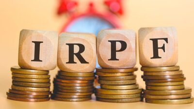 Letras IRPF en cubos sobre pilas de monedas
